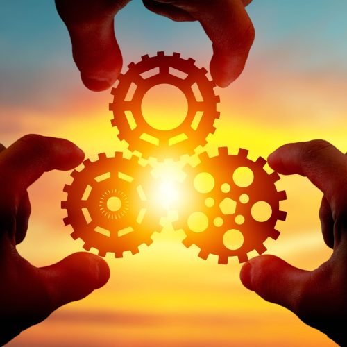 male-hand-holding-three-wooden-cog-gear-wheel-blue-sky-background-sunshine-yellow-sky-min